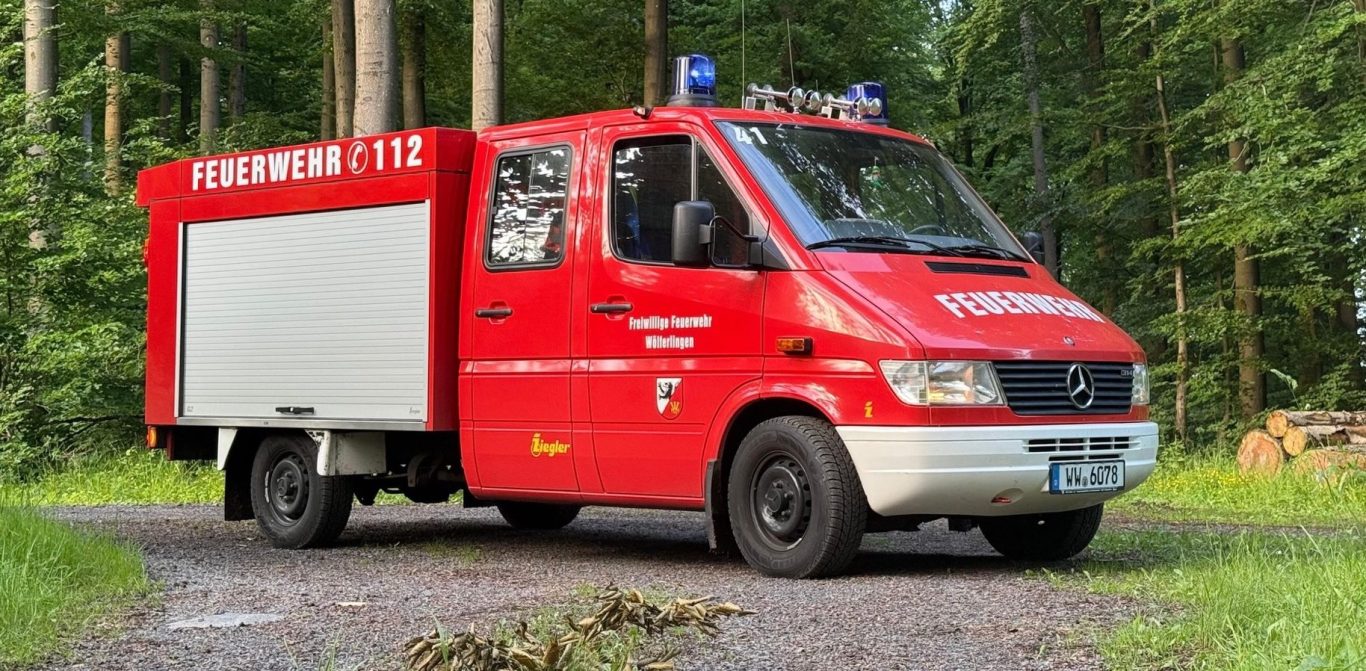 Feuerwehrauto Wölferlingen Rotes Feuerwehrfahrzeug steht auf einem Waldweg, umgeben von Bäumen.